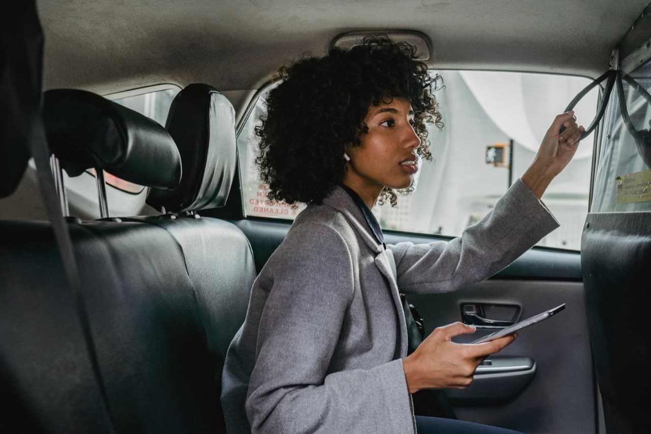 Une passagère, téléphone en main, à l’arrière d’une voiture